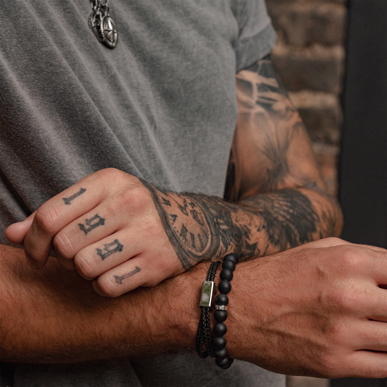 Men's 10mm black onyx beaded bracelet on model with black leather bracelet
