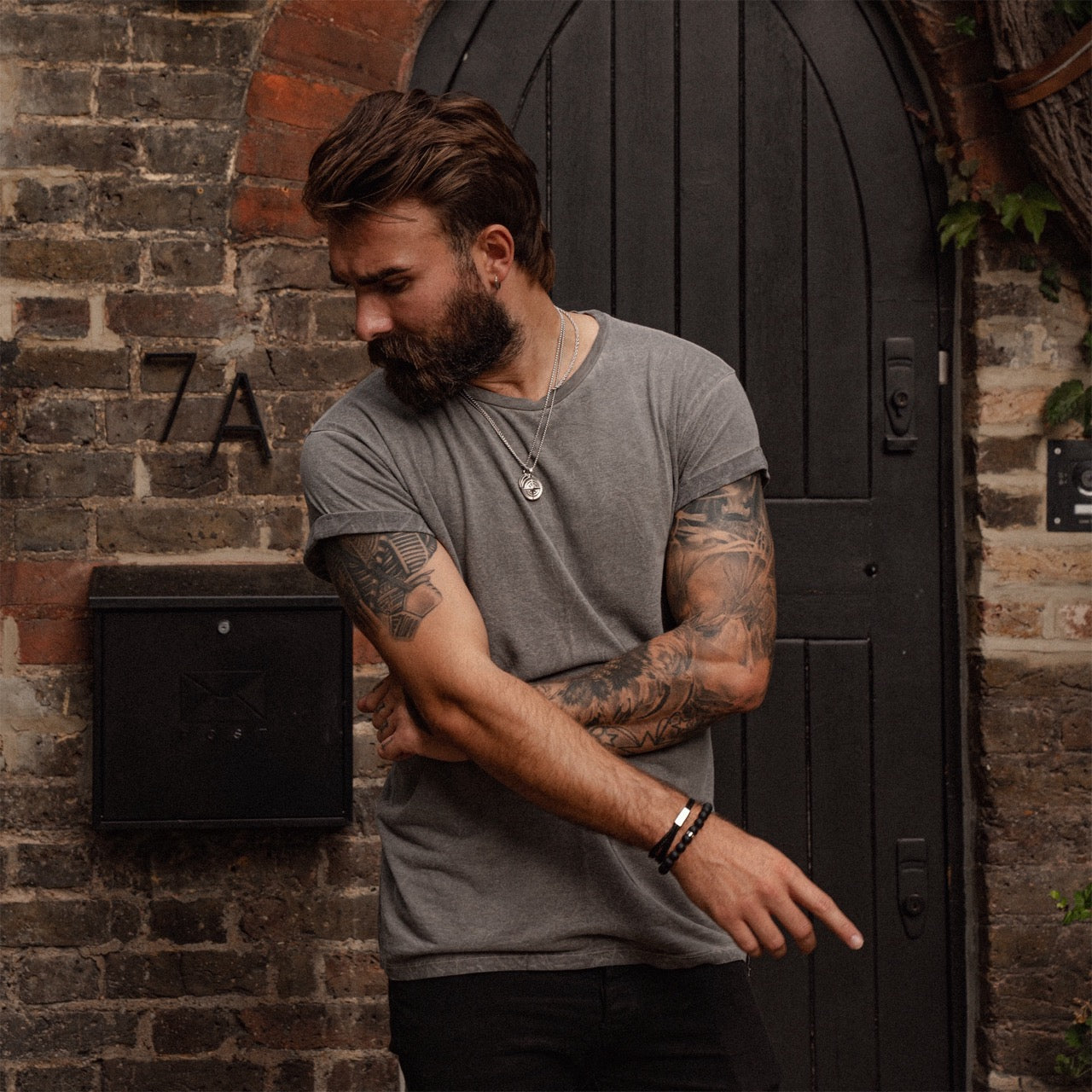 Men's 10mm black onyx beaded bracelet on model with compass pendant