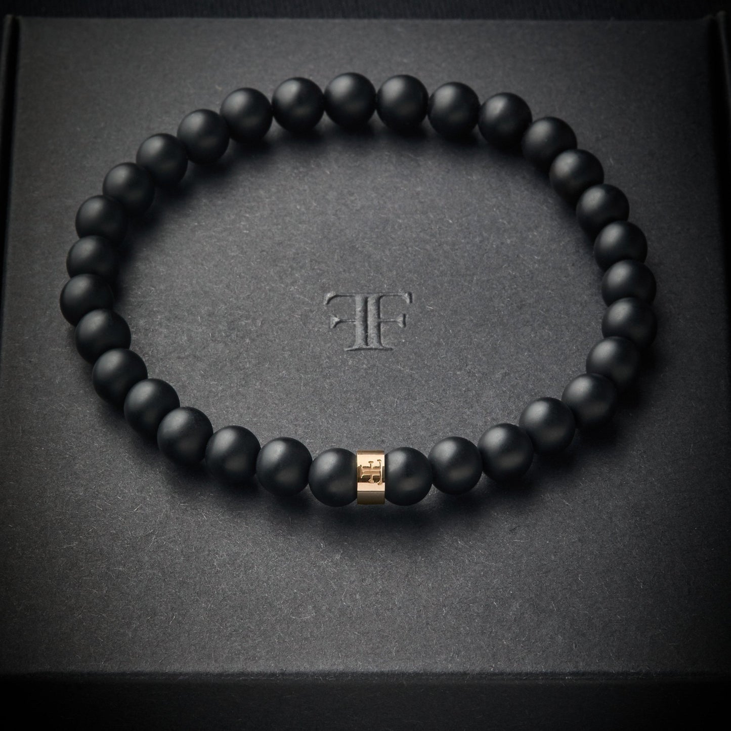 mens 6mm black and gold beaded stone bracelet on packaging box