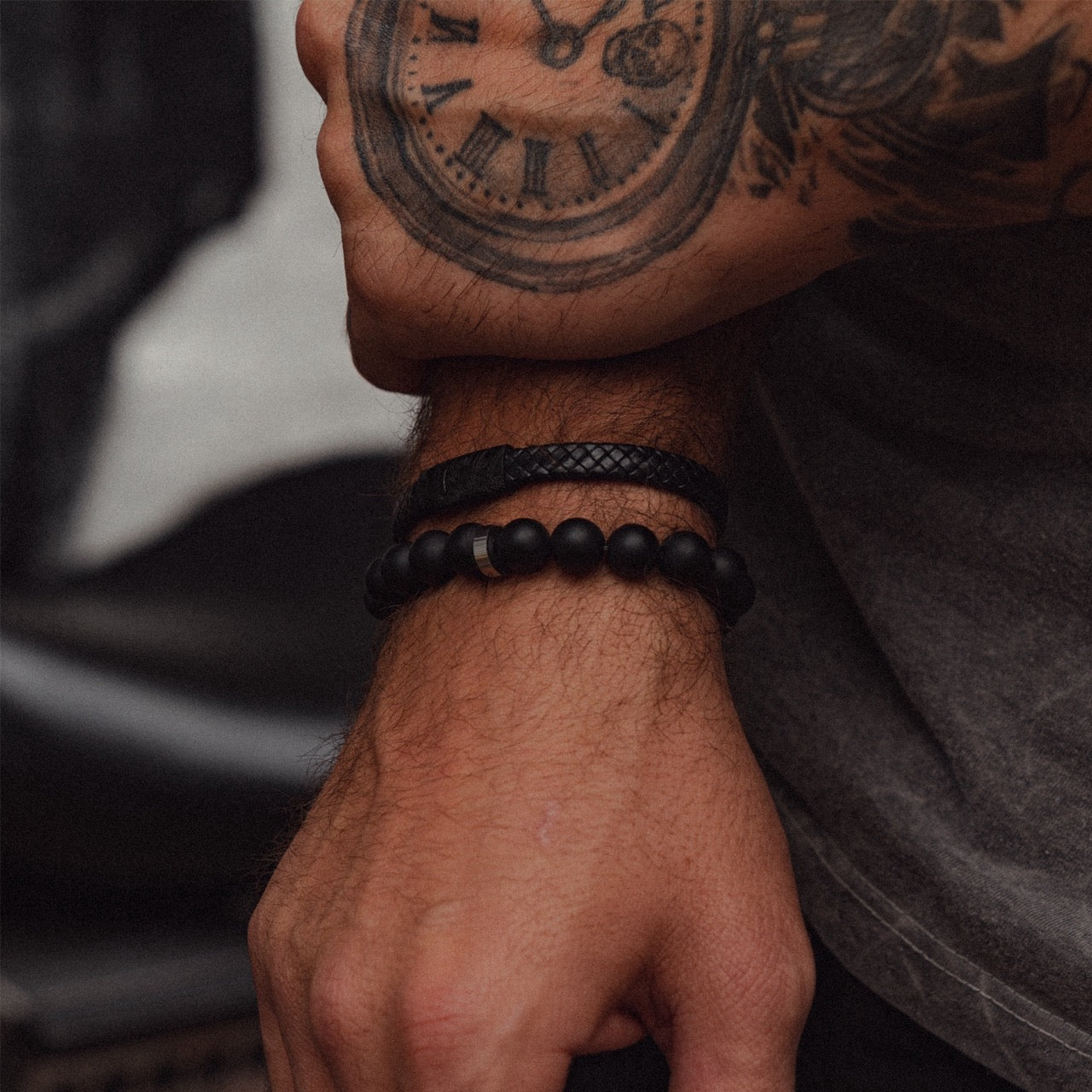 Men's 10mm black onyx beaded bracelet on model with leather bracelet