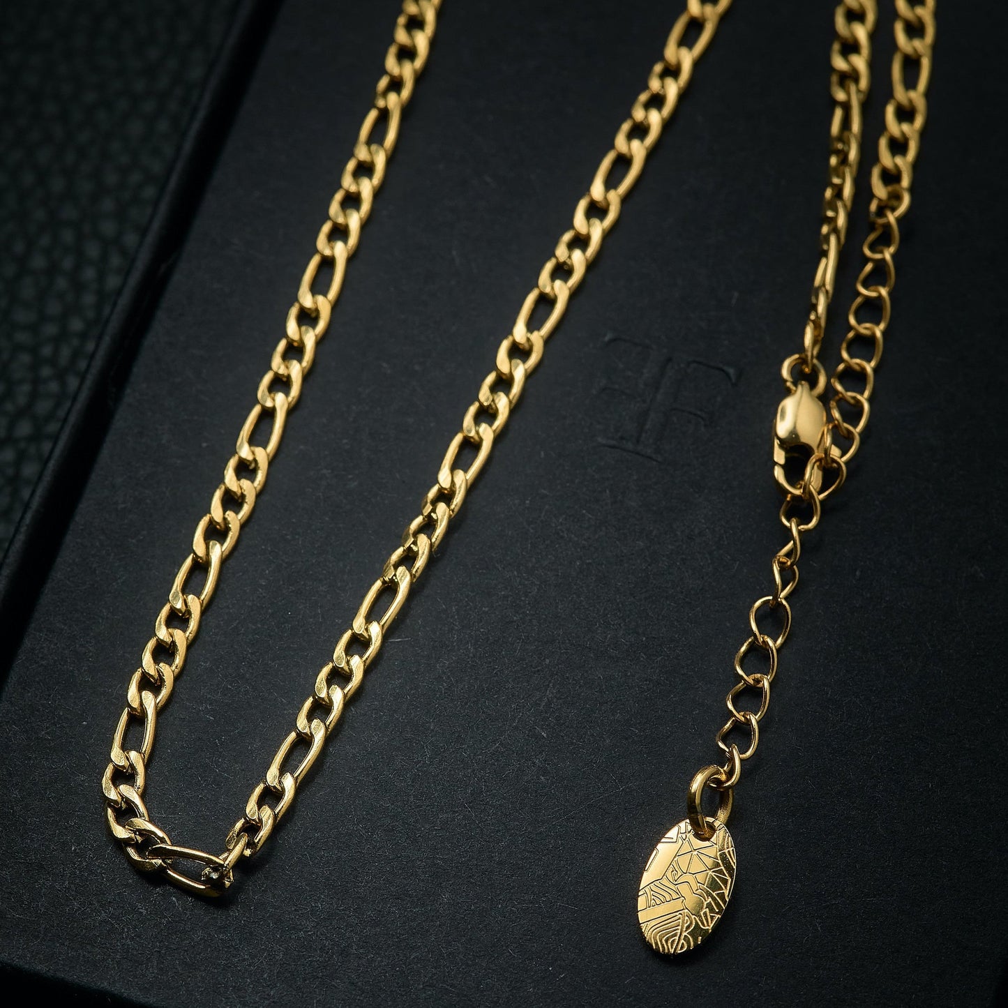 Men's gold figaro layering chain necklace on packaging box