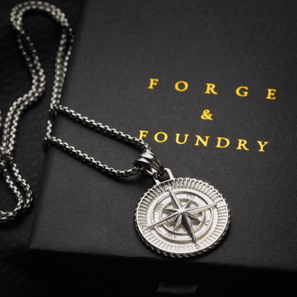 Men's silver compass pendant necklace on packaging box
