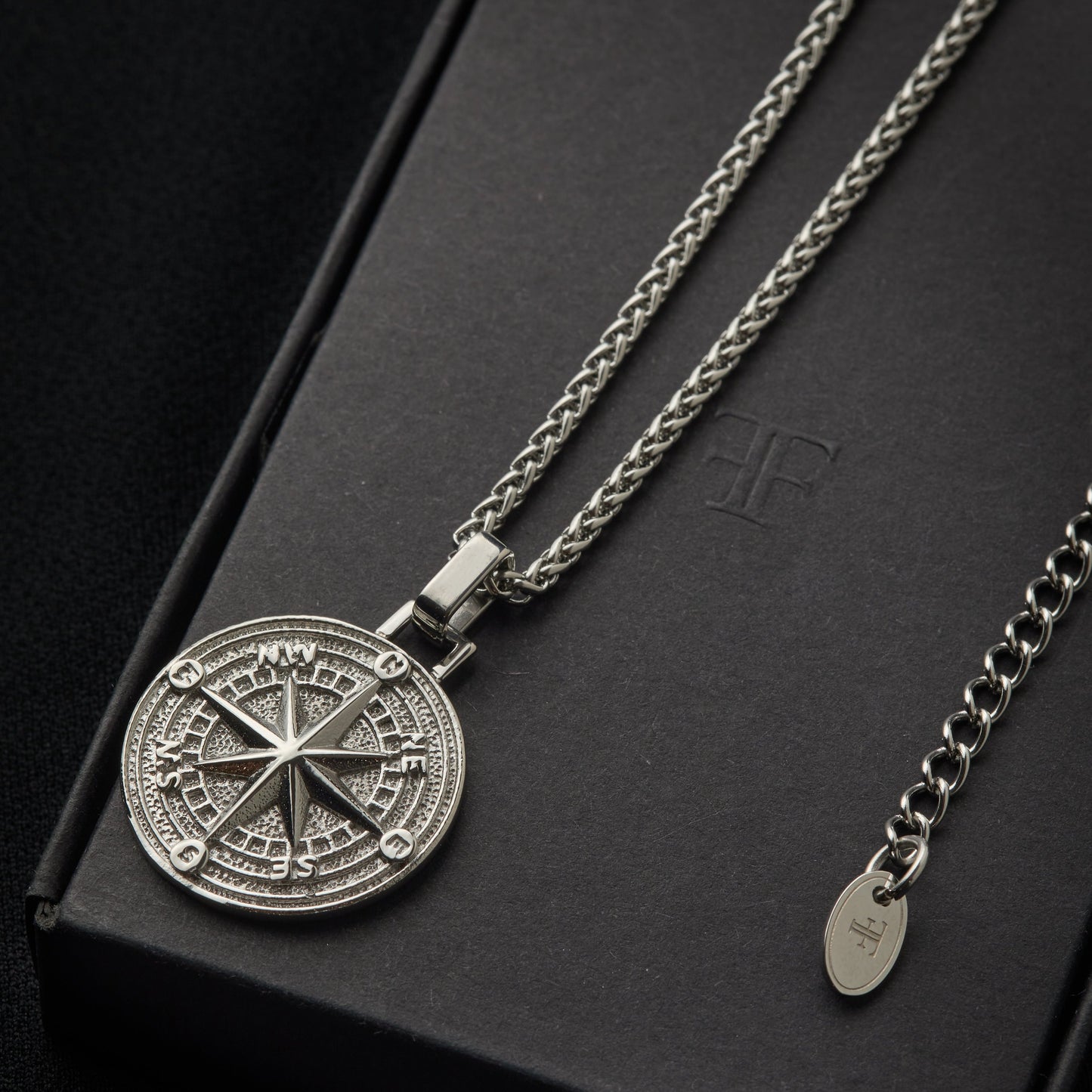 Mens stainless steel compass pendant on packaging box