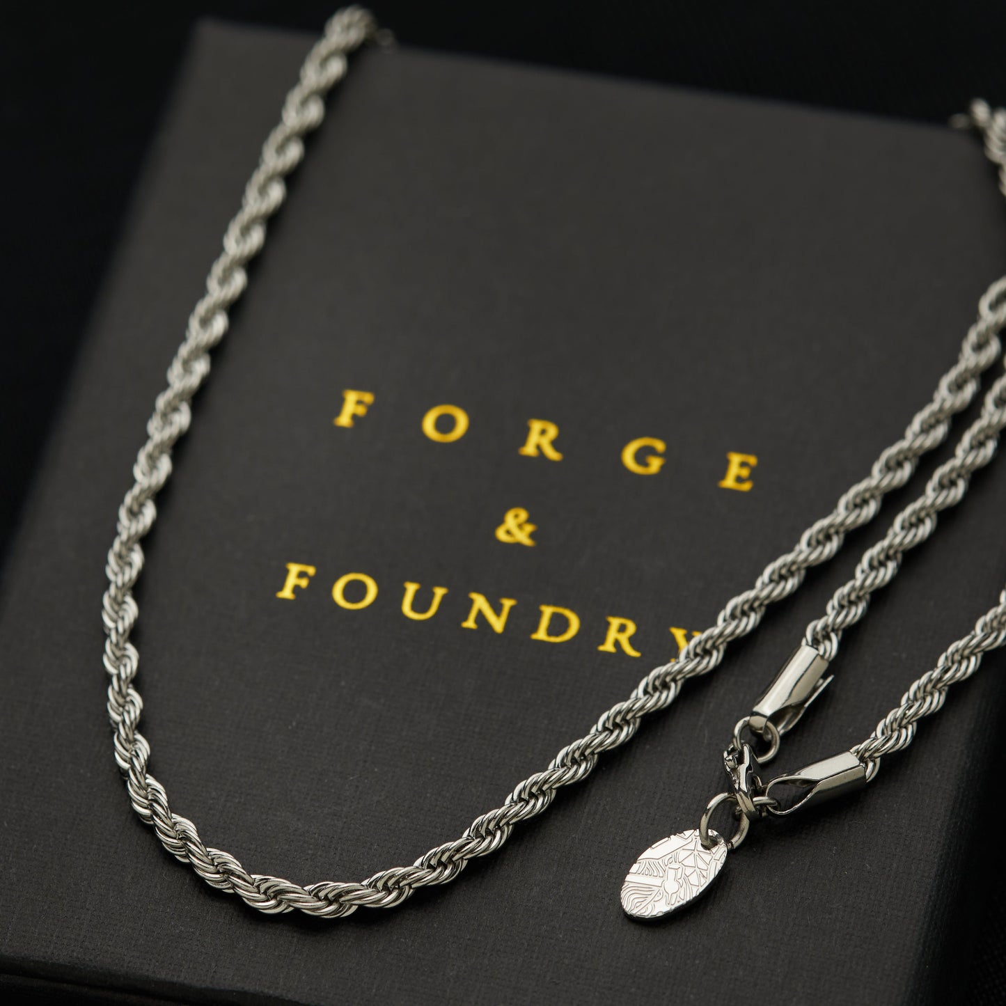 Men's silver rope chain necklace on packaging box