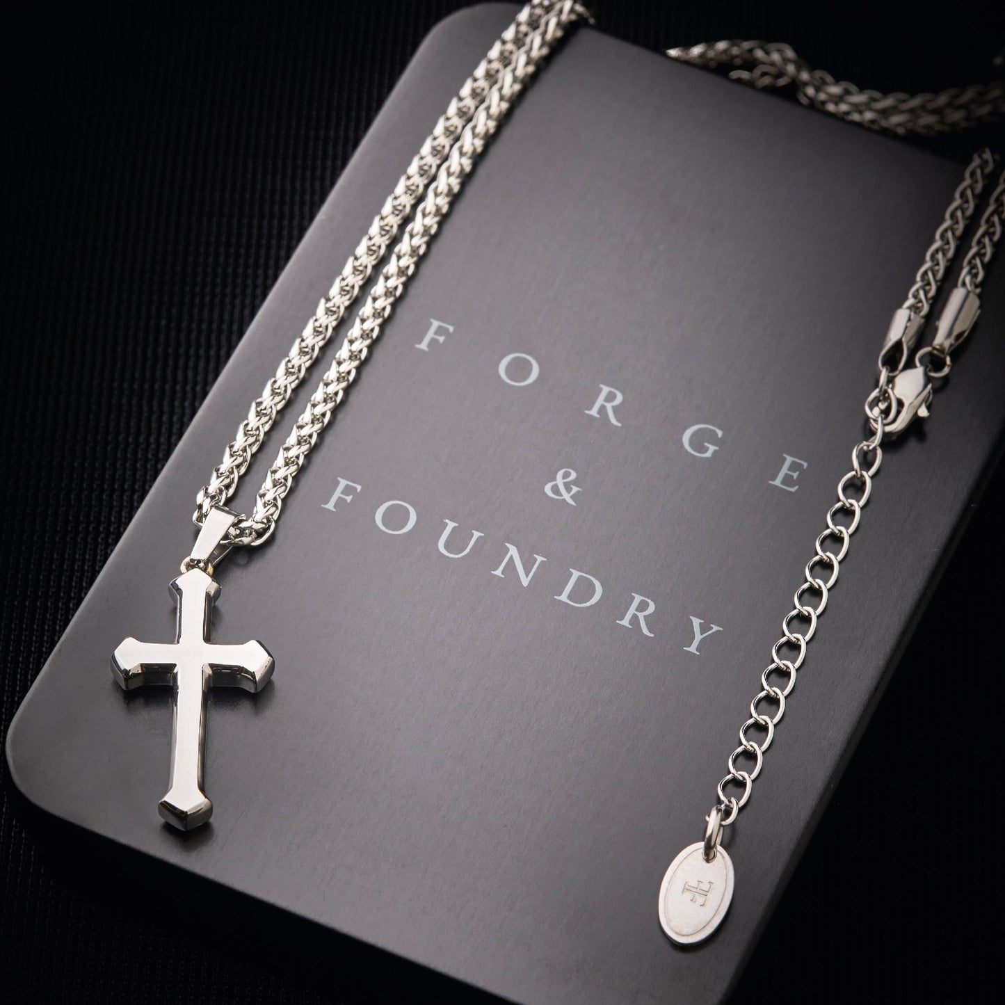 Men's silver cross pendant necklace on packaging box