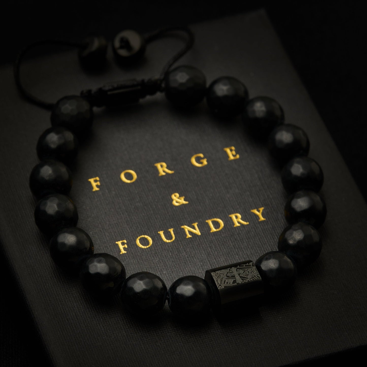 Men's black faceted adjustable onyx bead bracelet on packaging box