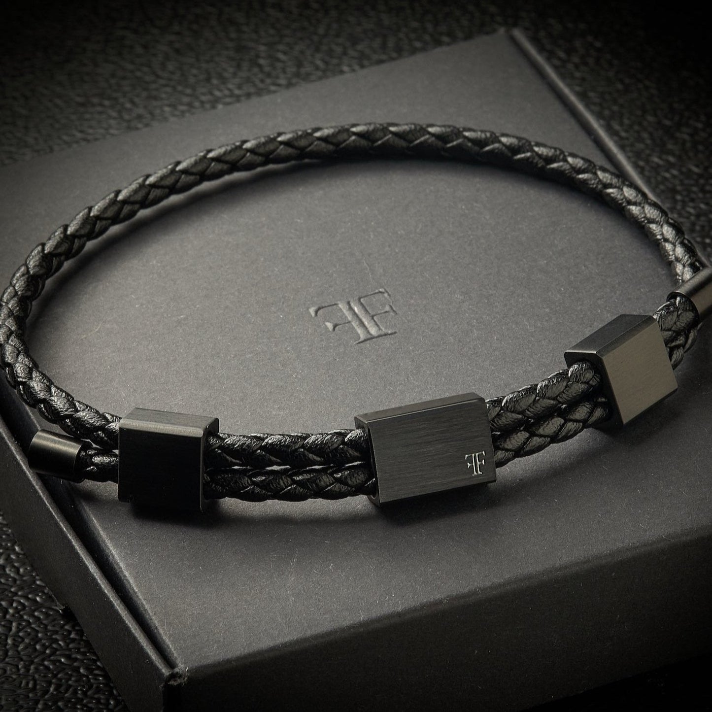 triple clasp black leather bracelet and gold compass on packaging