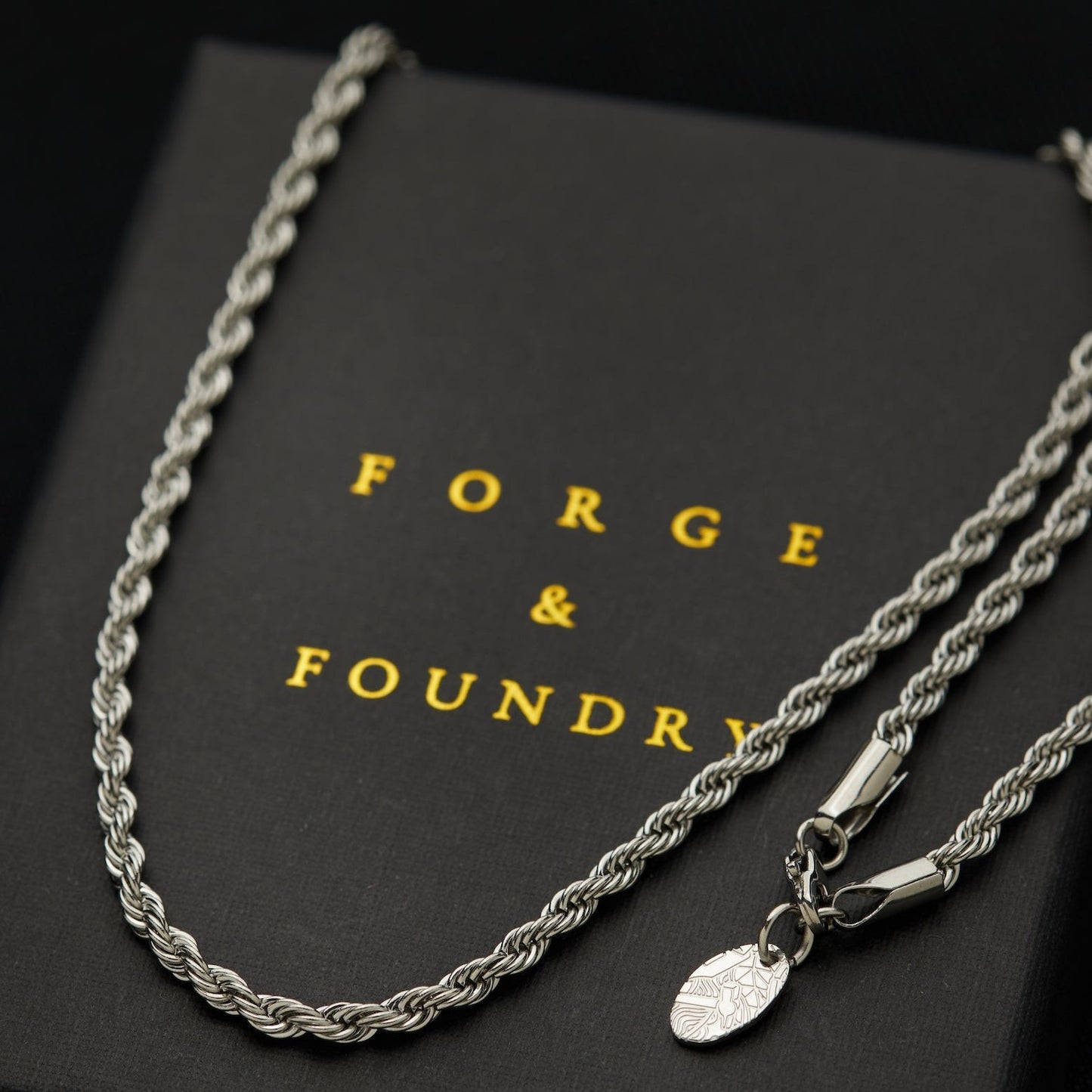 Men's silver rope chain necklace on packaging box