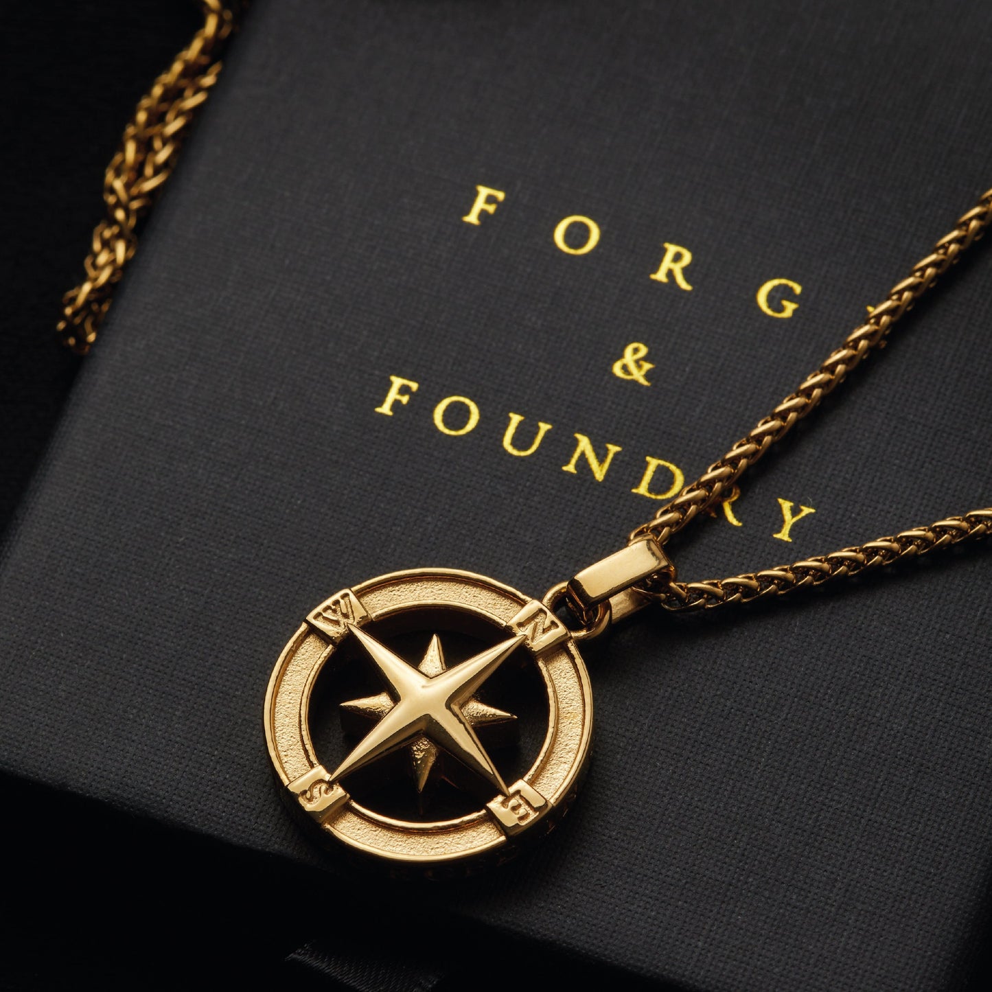 Men's gold North Star pendant necklace on packaging box