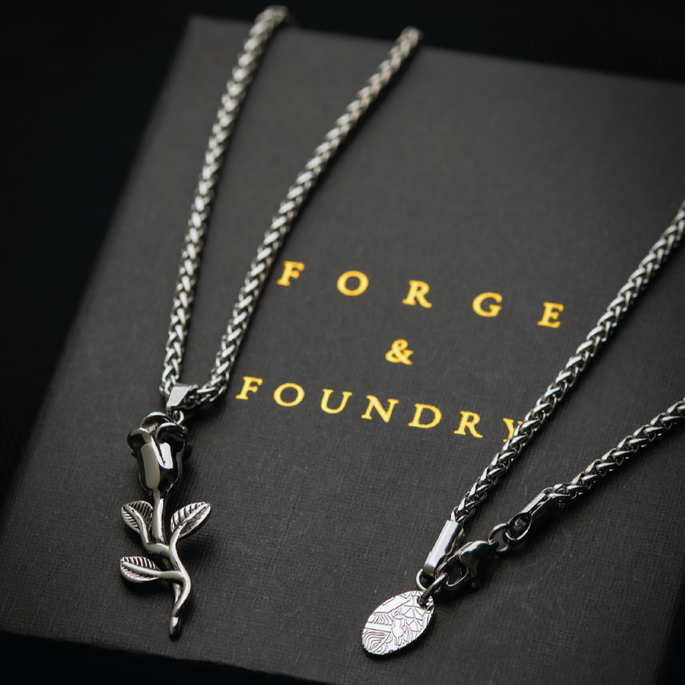 Men's silver rose pendant necklace on packaging box