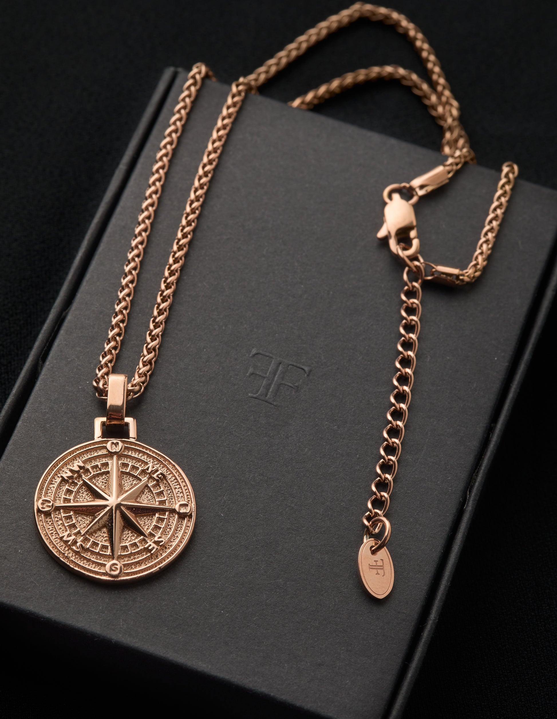 Men's rose gold compass pendant on packaging