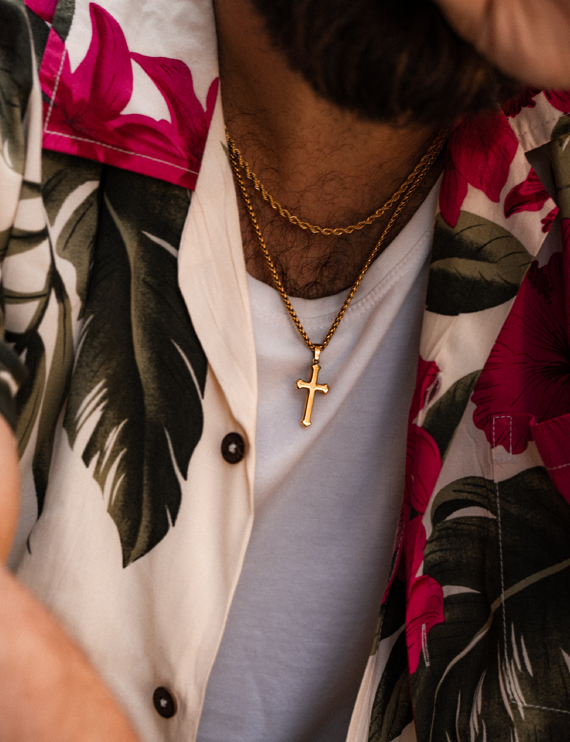 Mens gold cross pendant on model with rope layering chain