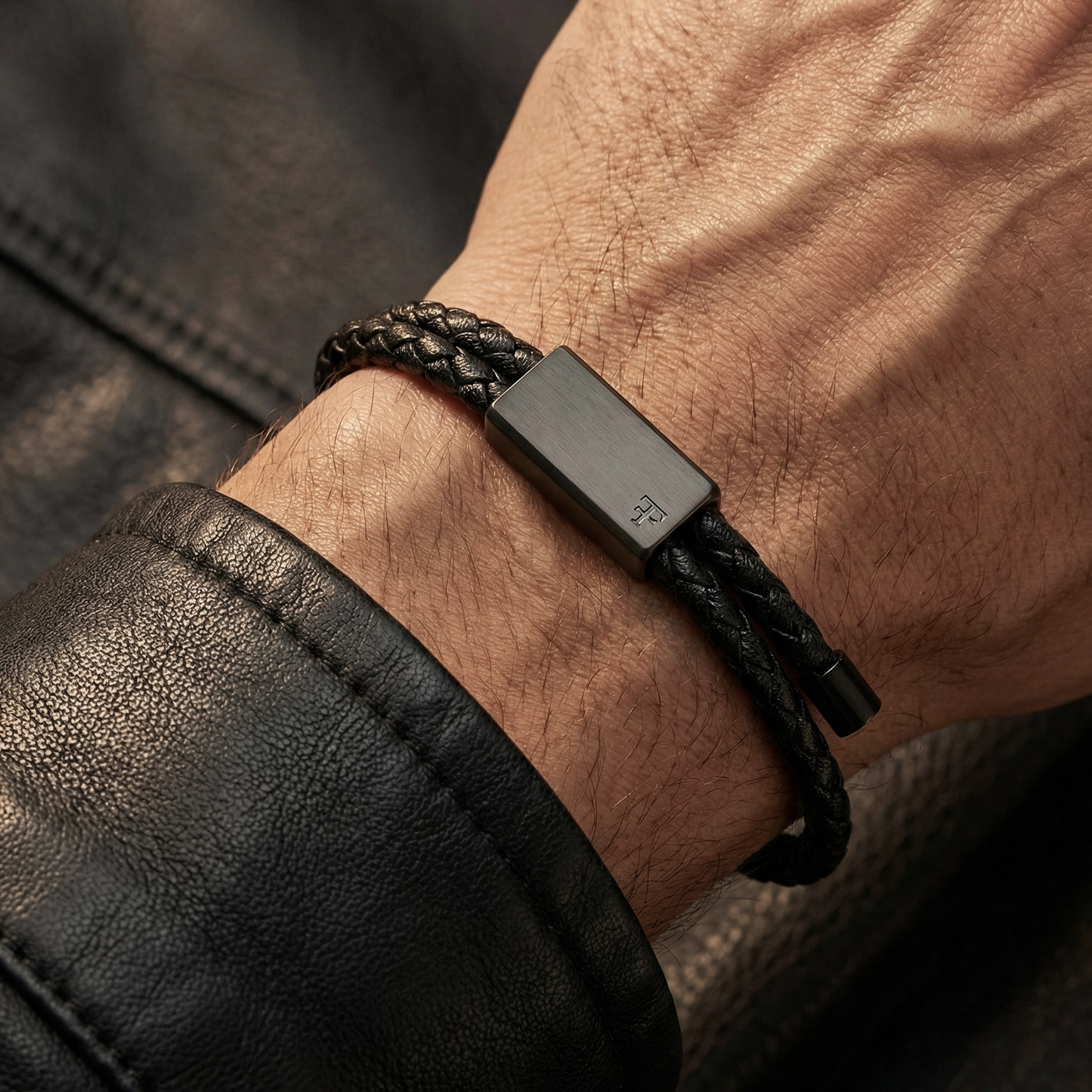 Black braided leather bracelet on a wrist with a dark background