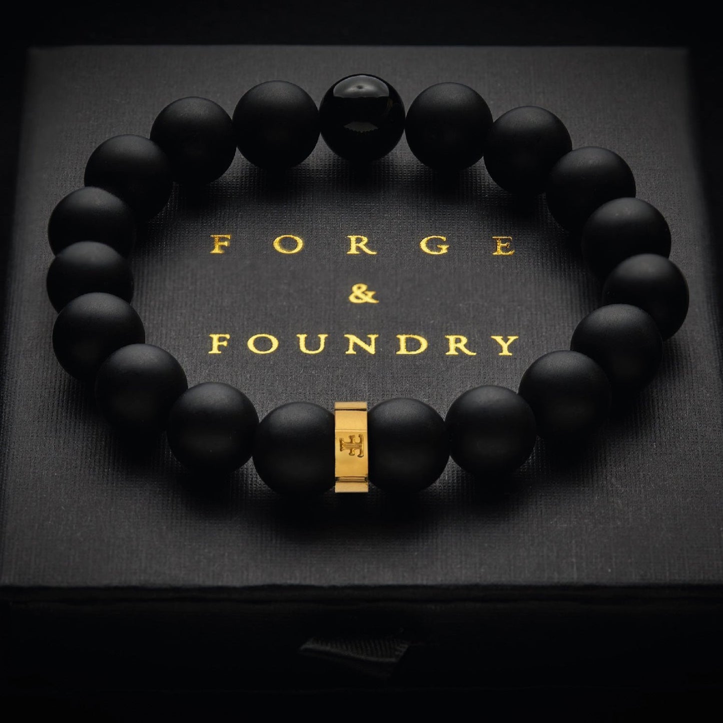 Mens gold and black onyx bead and stone bracelet with a leather bracelet on packaging