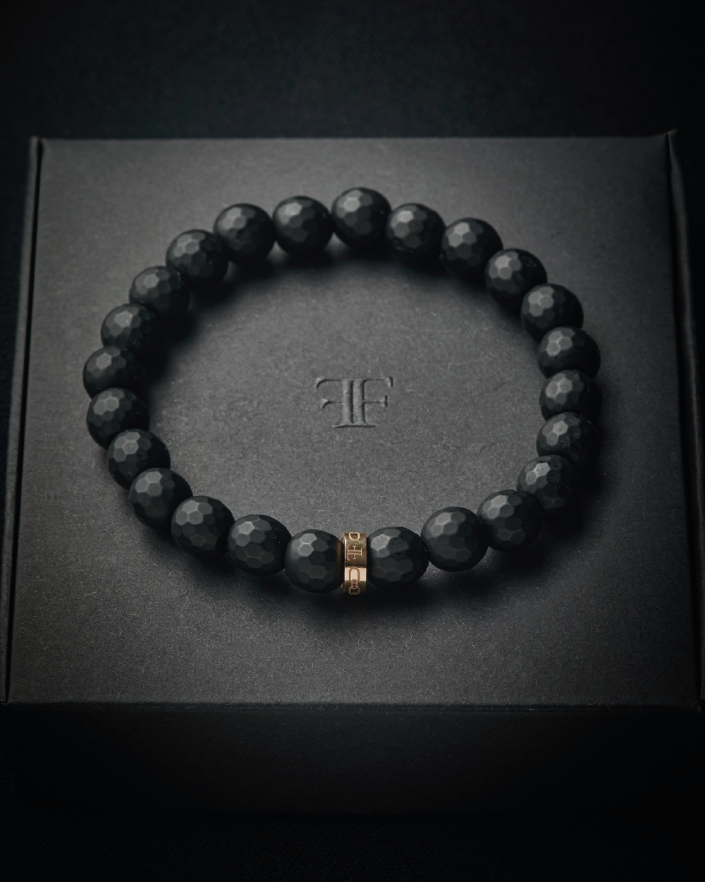 mens black faceted onyx bead stone bracelet with gold bead on packaging