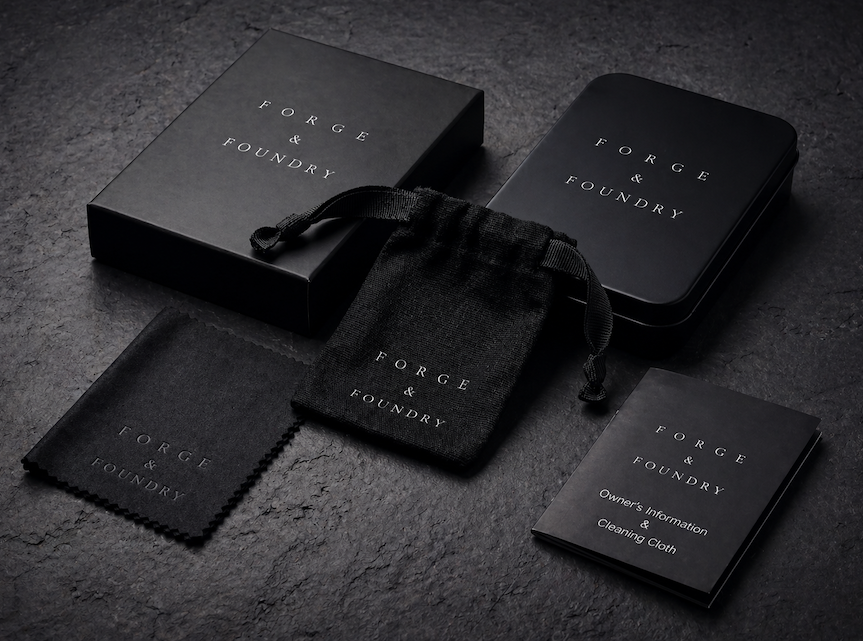 Black jewelry packaging set with 'Forge & Foundry' branding on a dark surface.