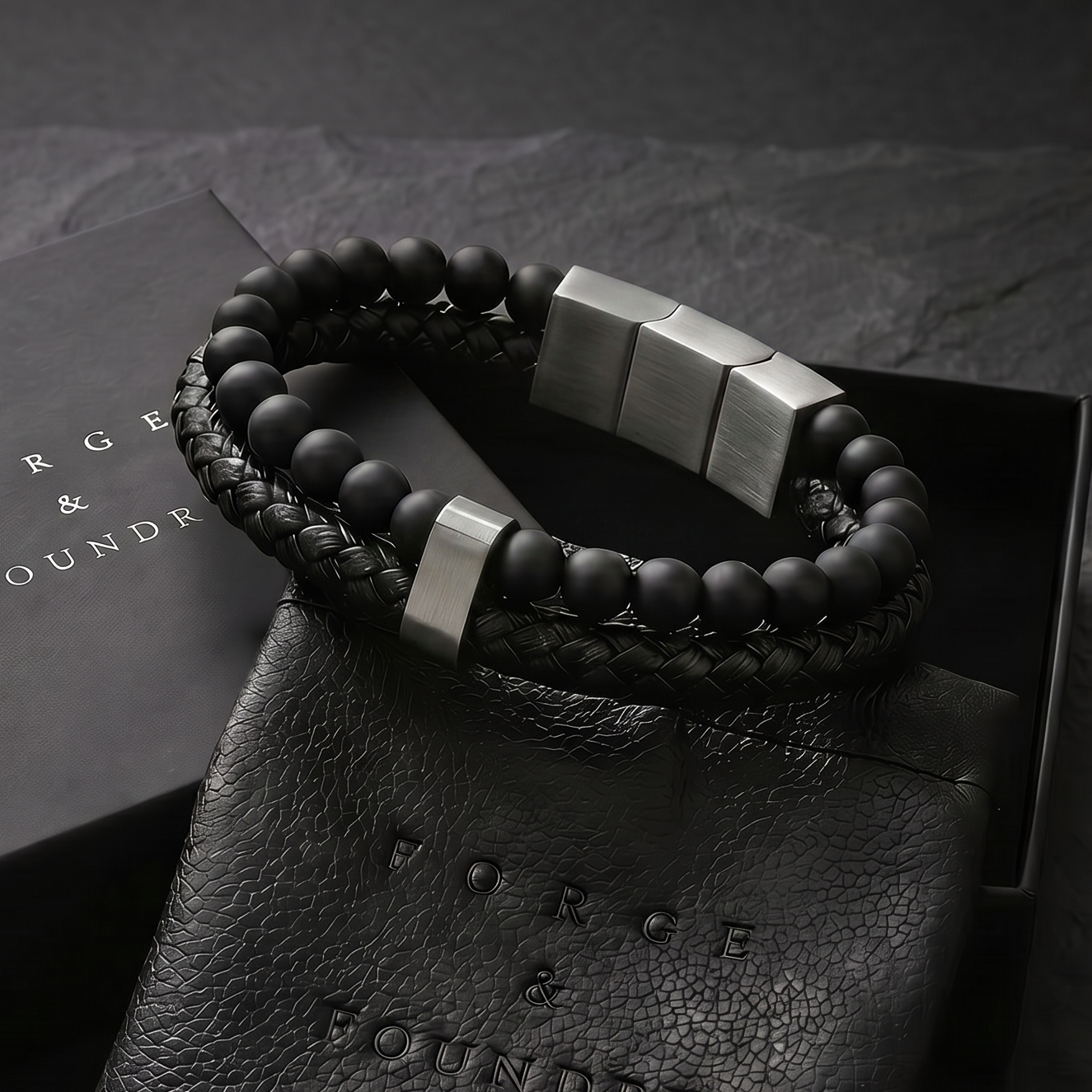 Bracelet and leather pouch on a dark surface with 'Forged & Foundry' branding.