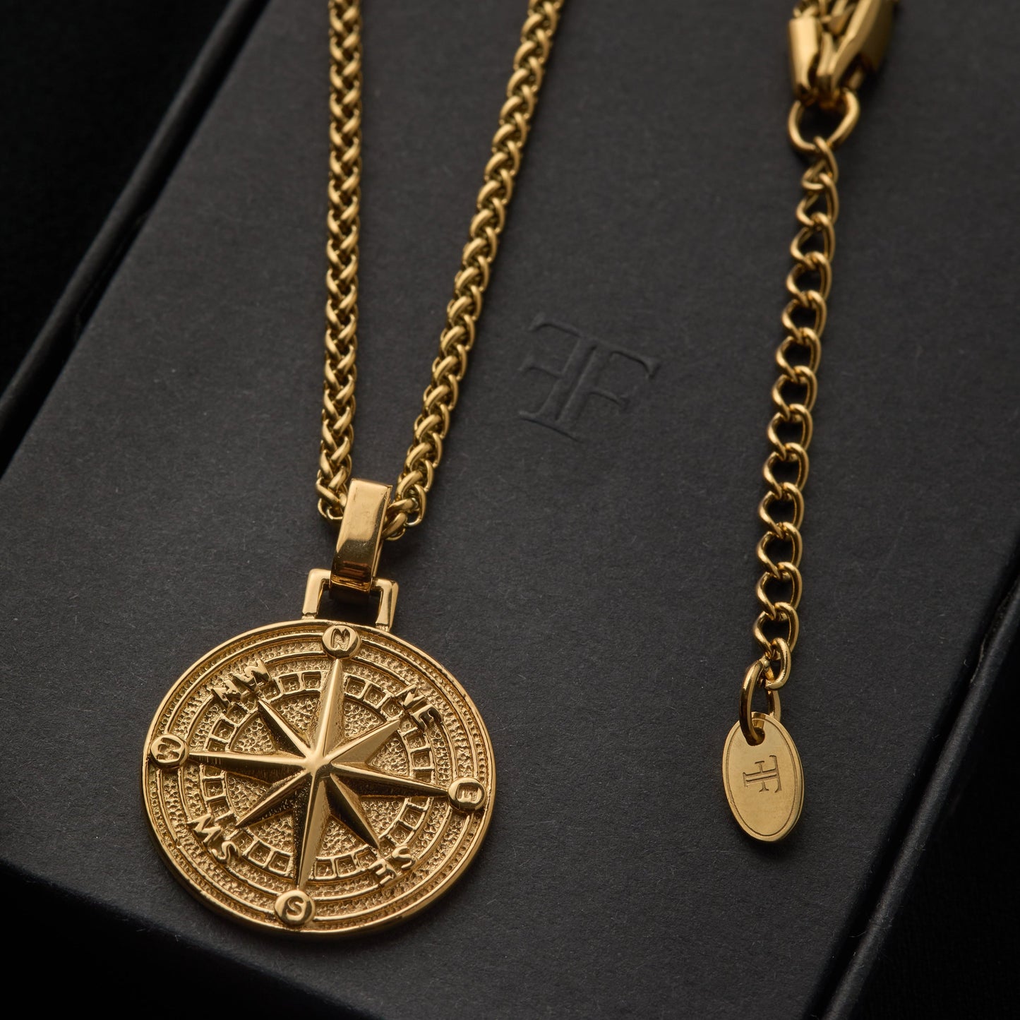 Men's gold compass pendant with wheat chain on packaging tin