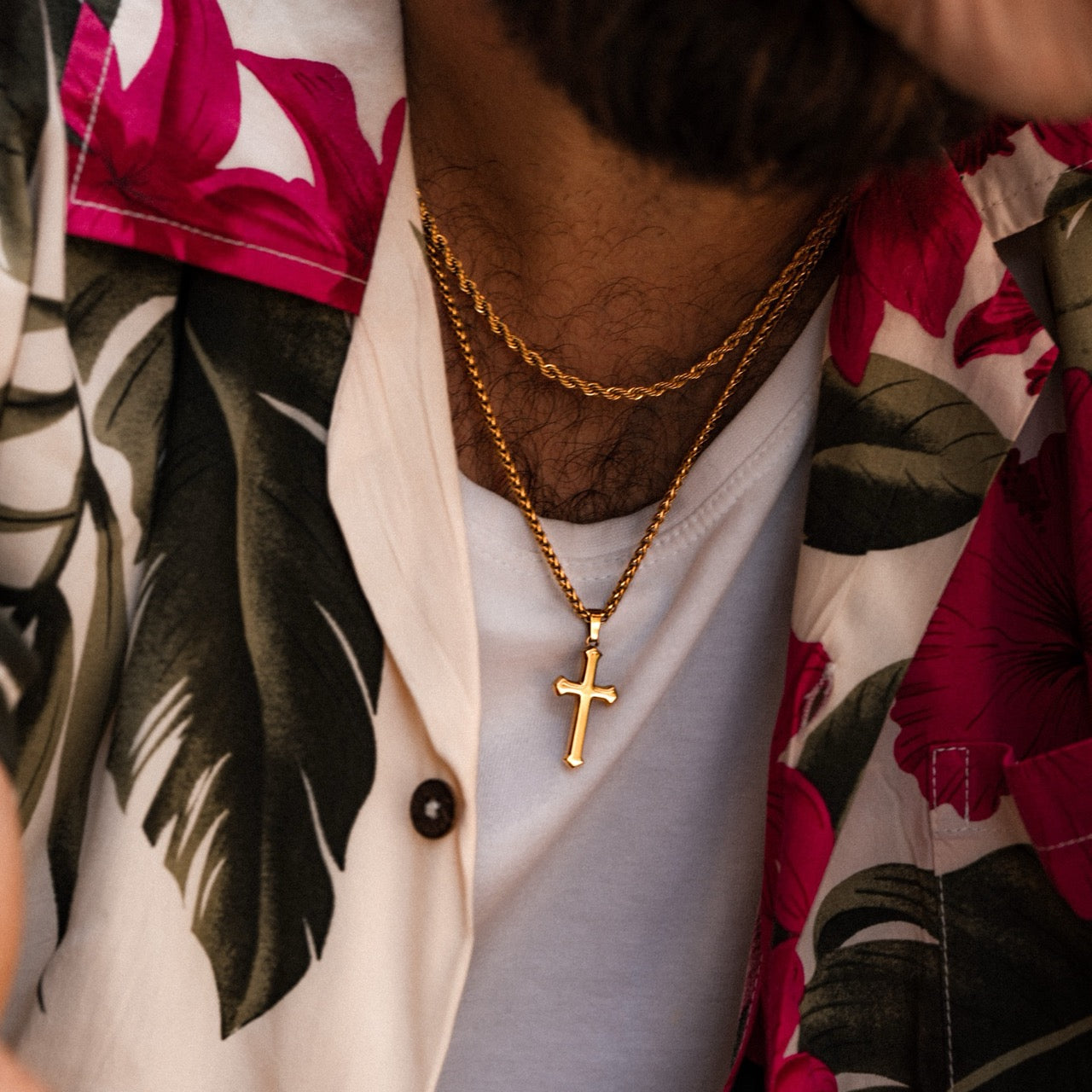 Men's gold cross pendant and wheat layering chain necklace on model