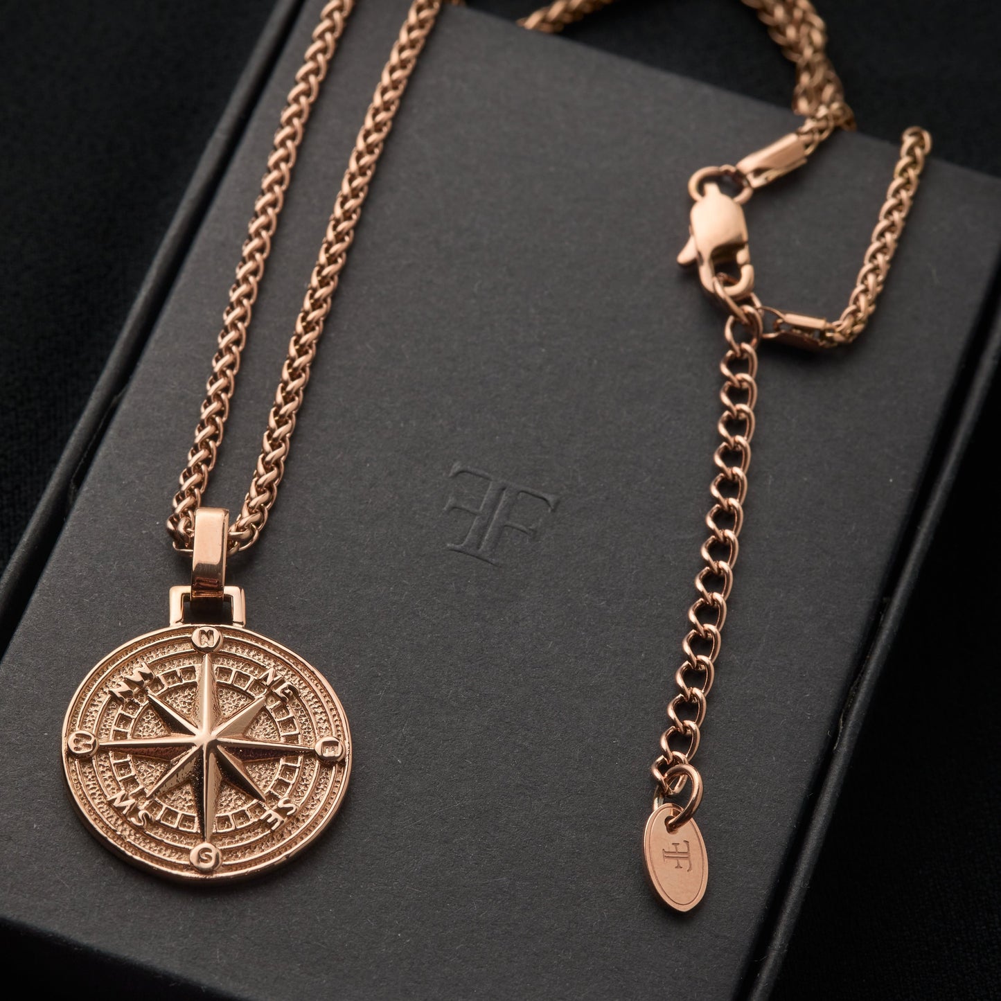 Men's rose gold compass pendant on packaging box